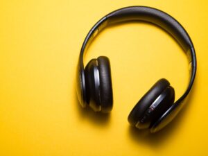 Foto de um fone de ouvido para escutar podcast em um fundo amarelo.